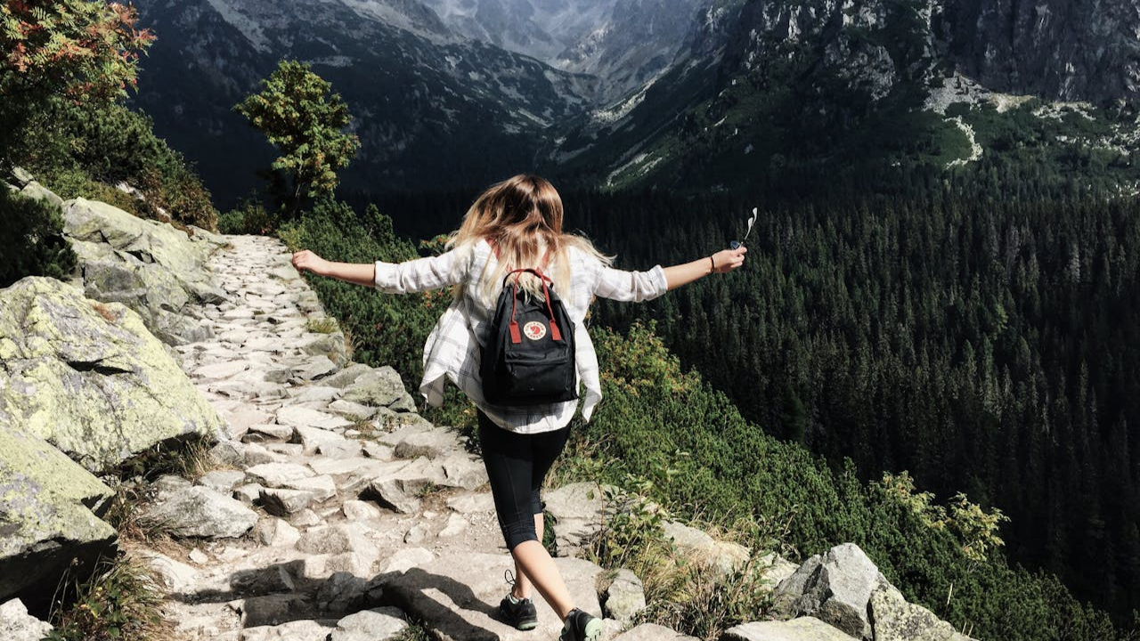 Portrait Photo of woman with her back turned hiking. Blurred Background.
