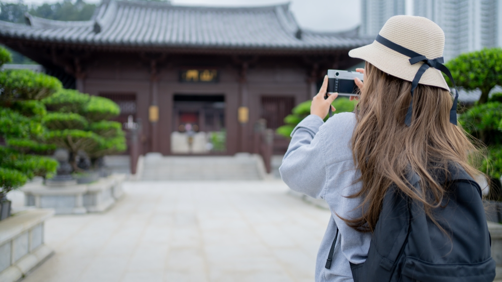Asian tourist, cute woman with long hair are traveling in Hong Kong along with map and her camera