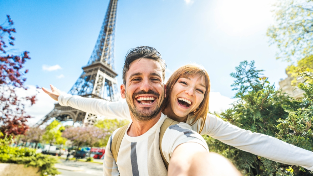 Happy couple of tourists taking selfie picture in front of Eiffel Tower in Paris, France