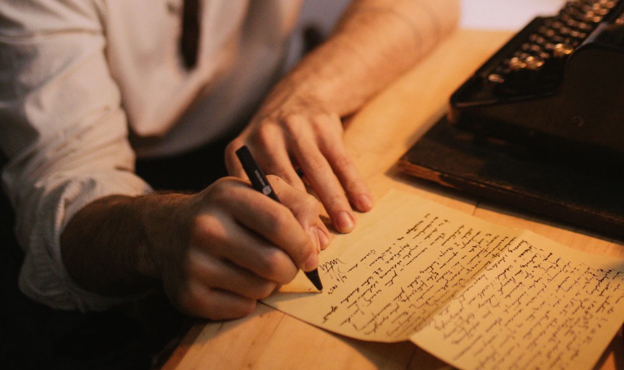 A man pens a letter using a typewriter, evoking a vintage writing atmosphere