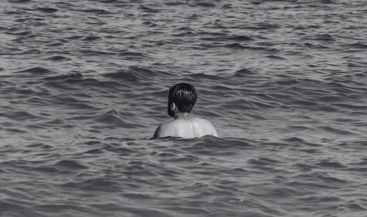 Back view of a man swimming in the turquoise waters of Dubai beach