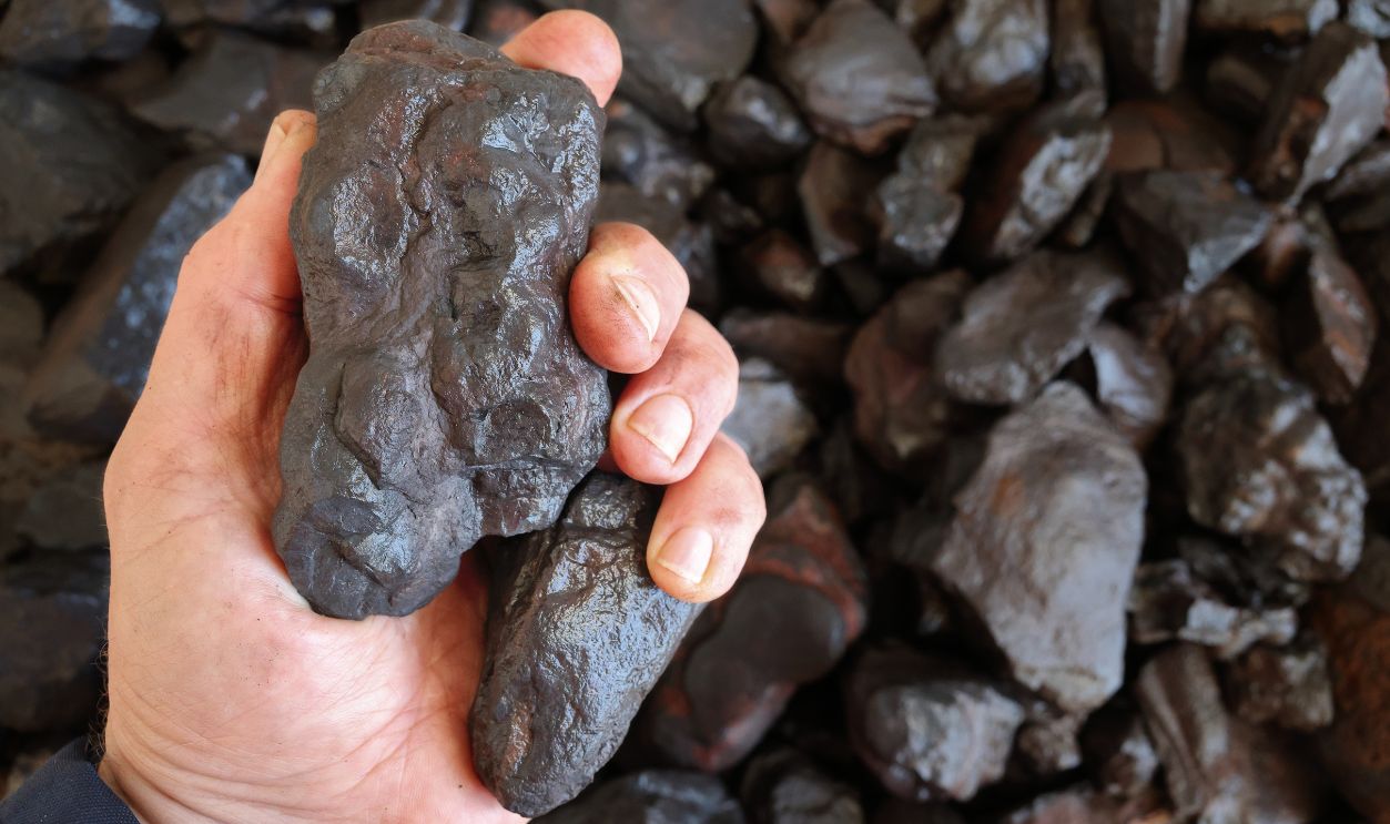 Wet, moist manganese (Mn) ore held in hand. Mining. Use for production of ferromanganese, stainless steel and batteries