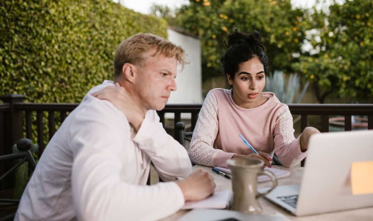 Two colleagues working together outside on a laptop, discussing ideas and strategies.