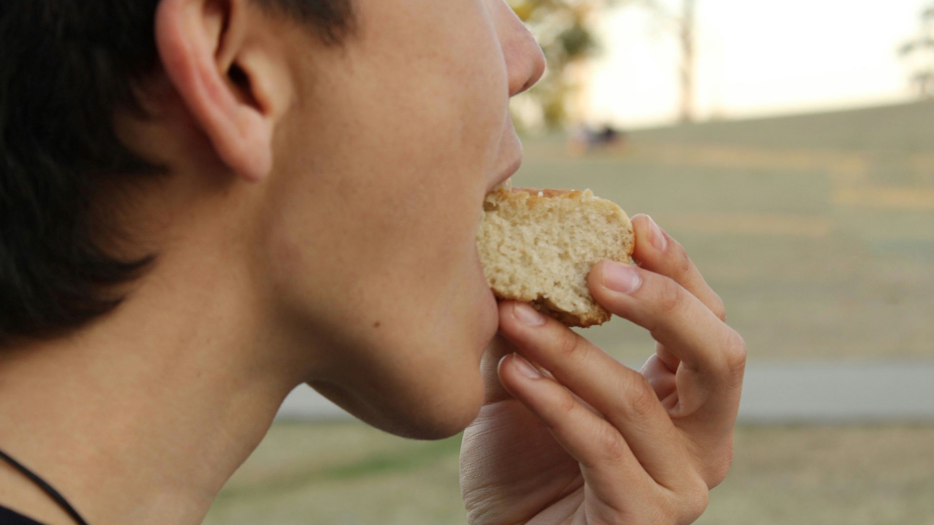A woman eating a sandwich in a park