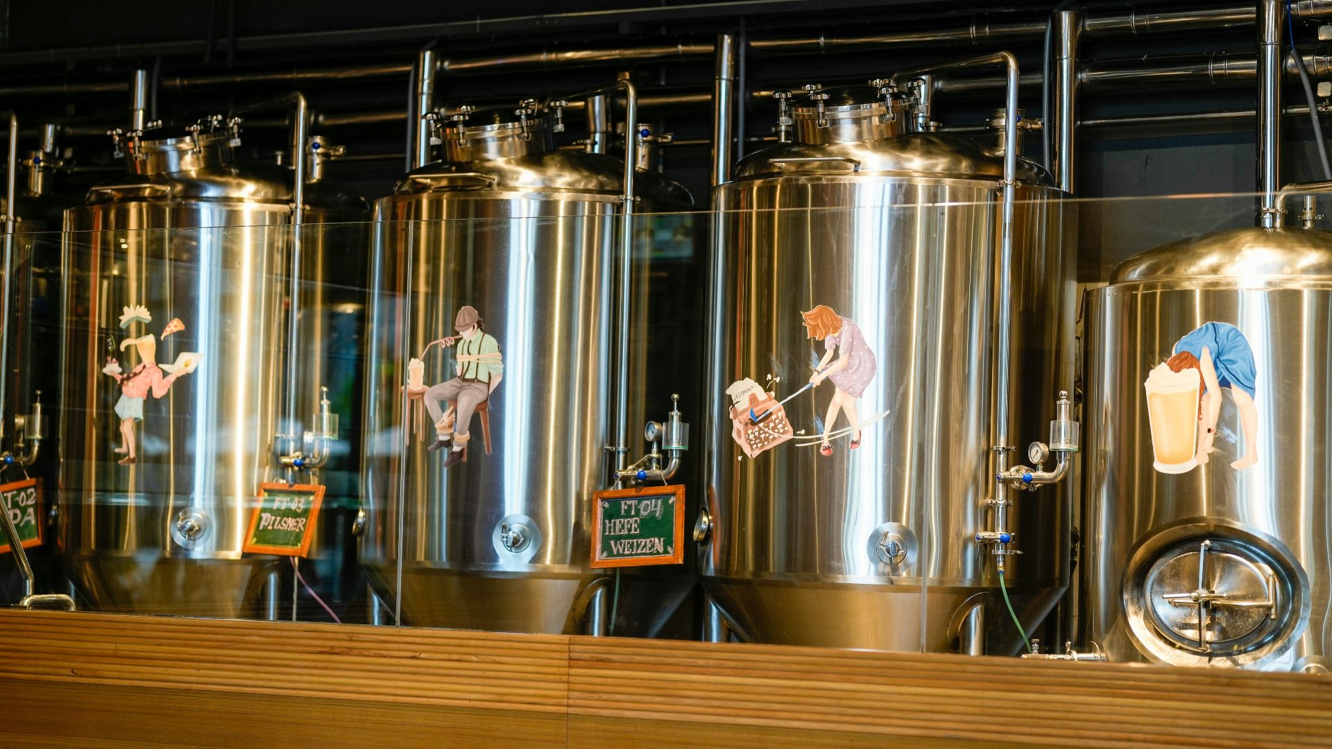 Stainless steel fermentation tanks in a brewery with cartoon decals.
