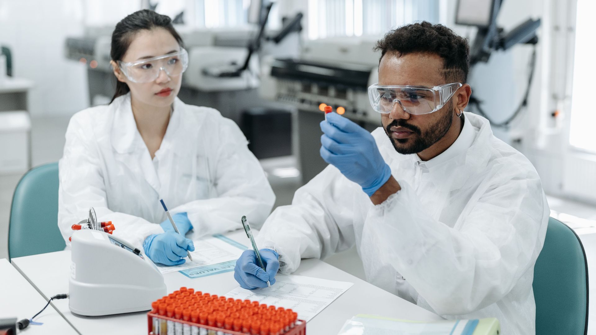 Two scientists in a lab examining samples and recording data in a healthcare setting.