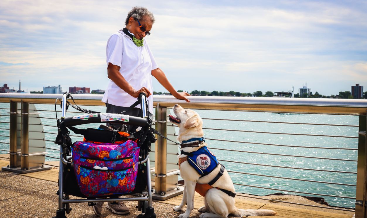 A senior woman enjoying a day by the water with her service dog