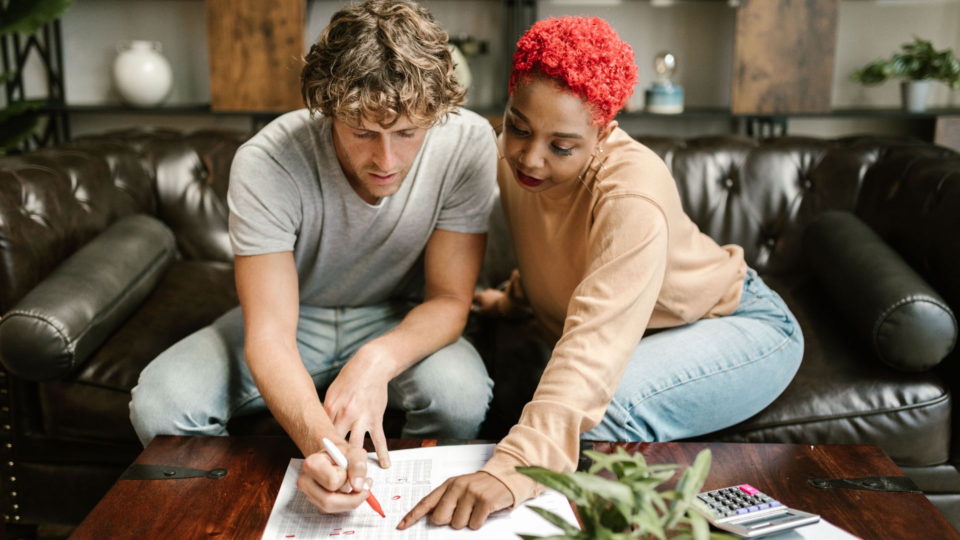 A man and woman collaborating on a project at home, focusing on paperwork.