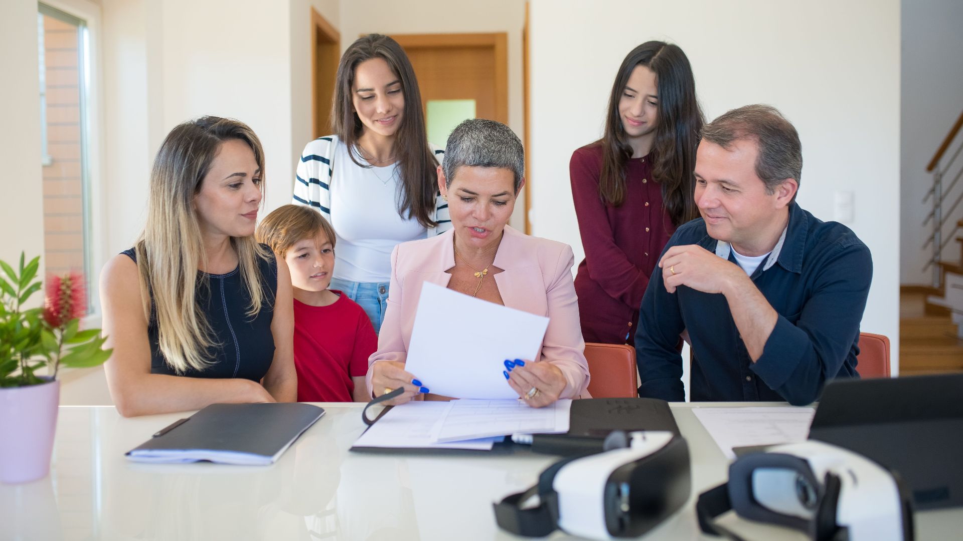 A family meeting with a female realtor reviewing documents in a bright, modern room.