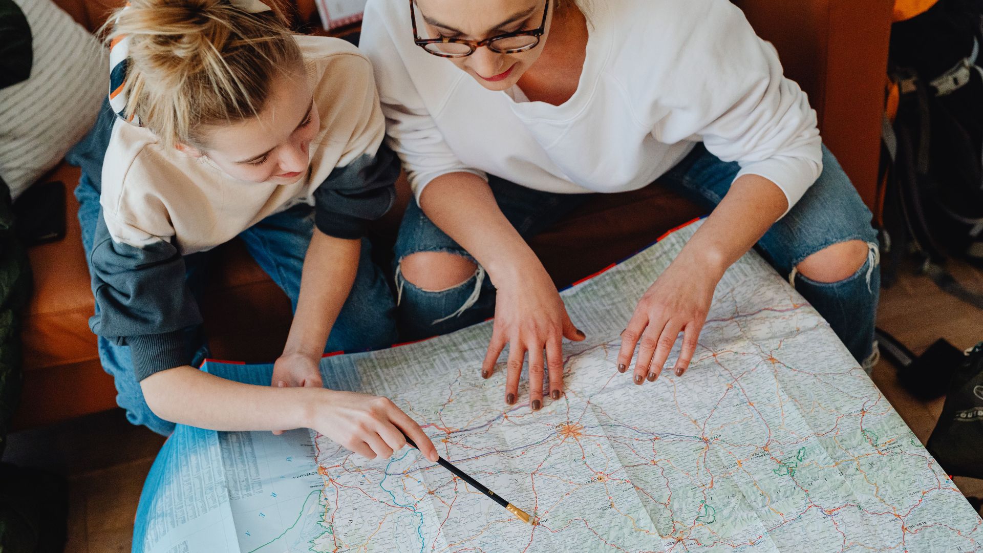 A mother and daughter plan their journey using a map, symbolizing adventure and bonding.