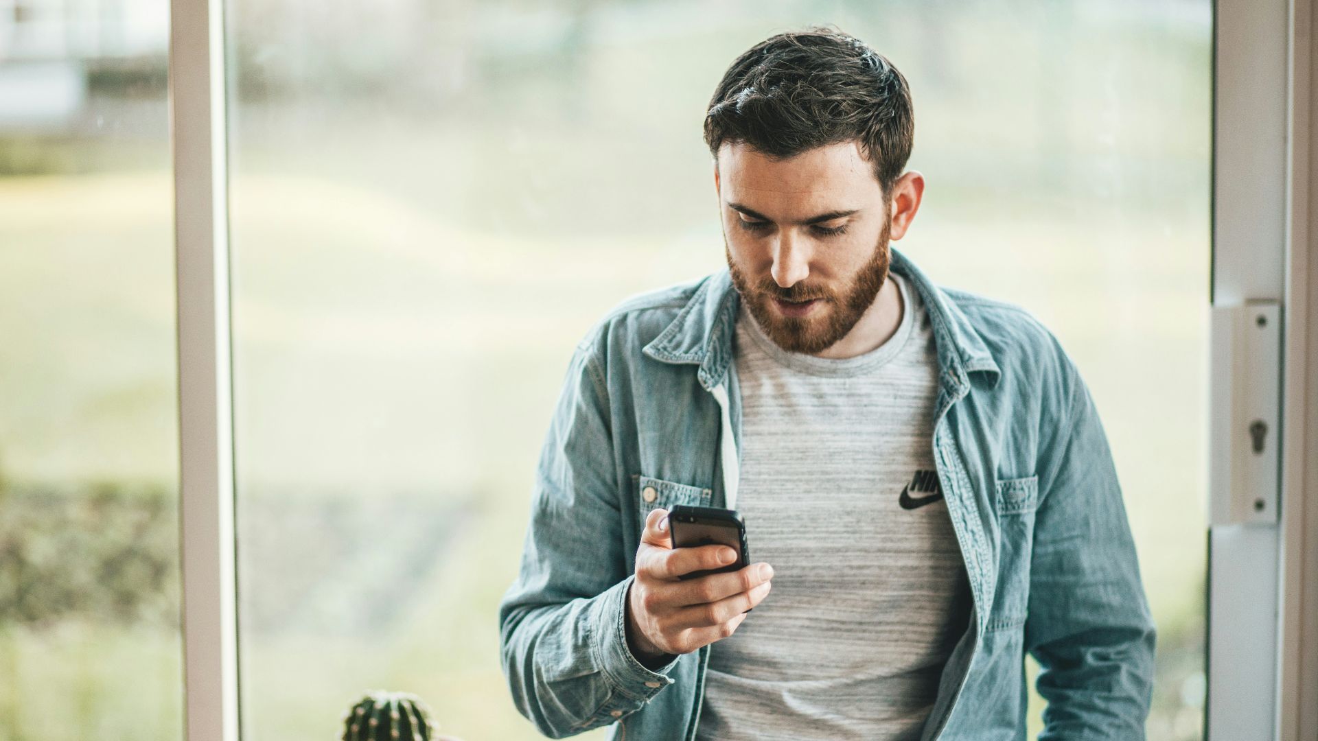 man holding a smartphone near the window