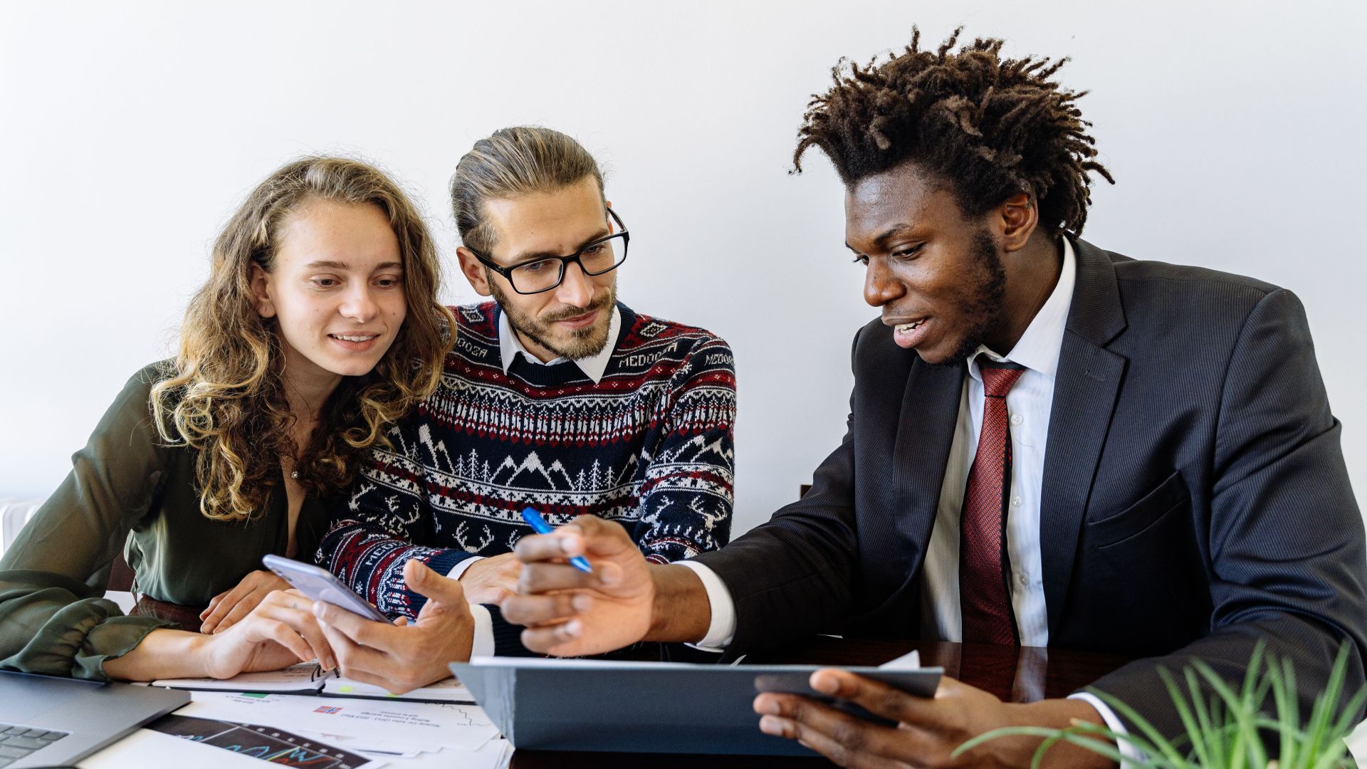 Three professionals engaging in a collaborative business meeting in a modern office environment.