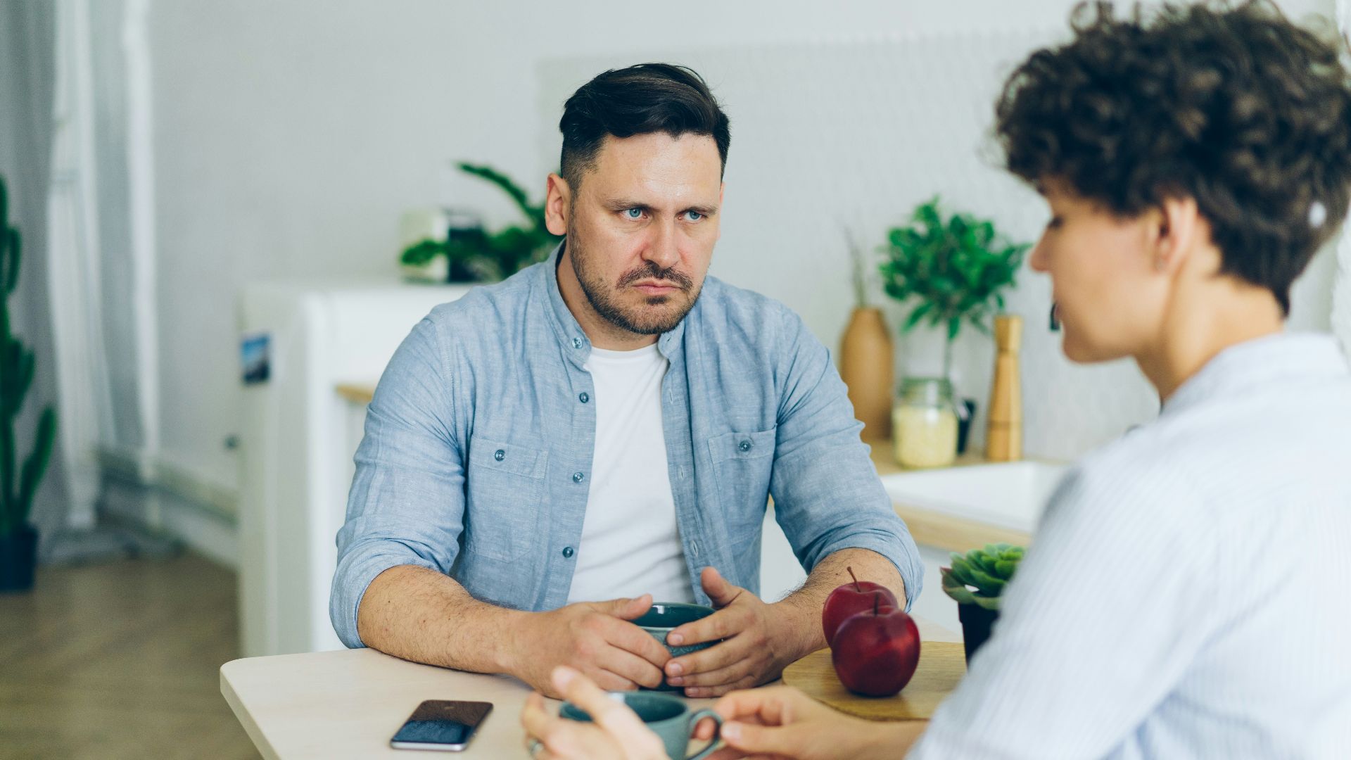a man sitting at a table talking to a woman