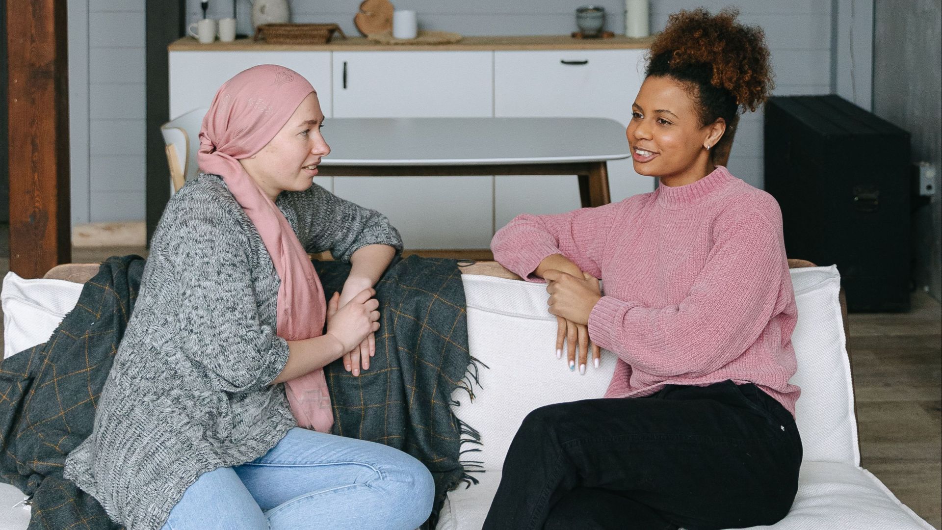 Two women having a heartfelt conversation on a couch, symbolizing support and friendship.