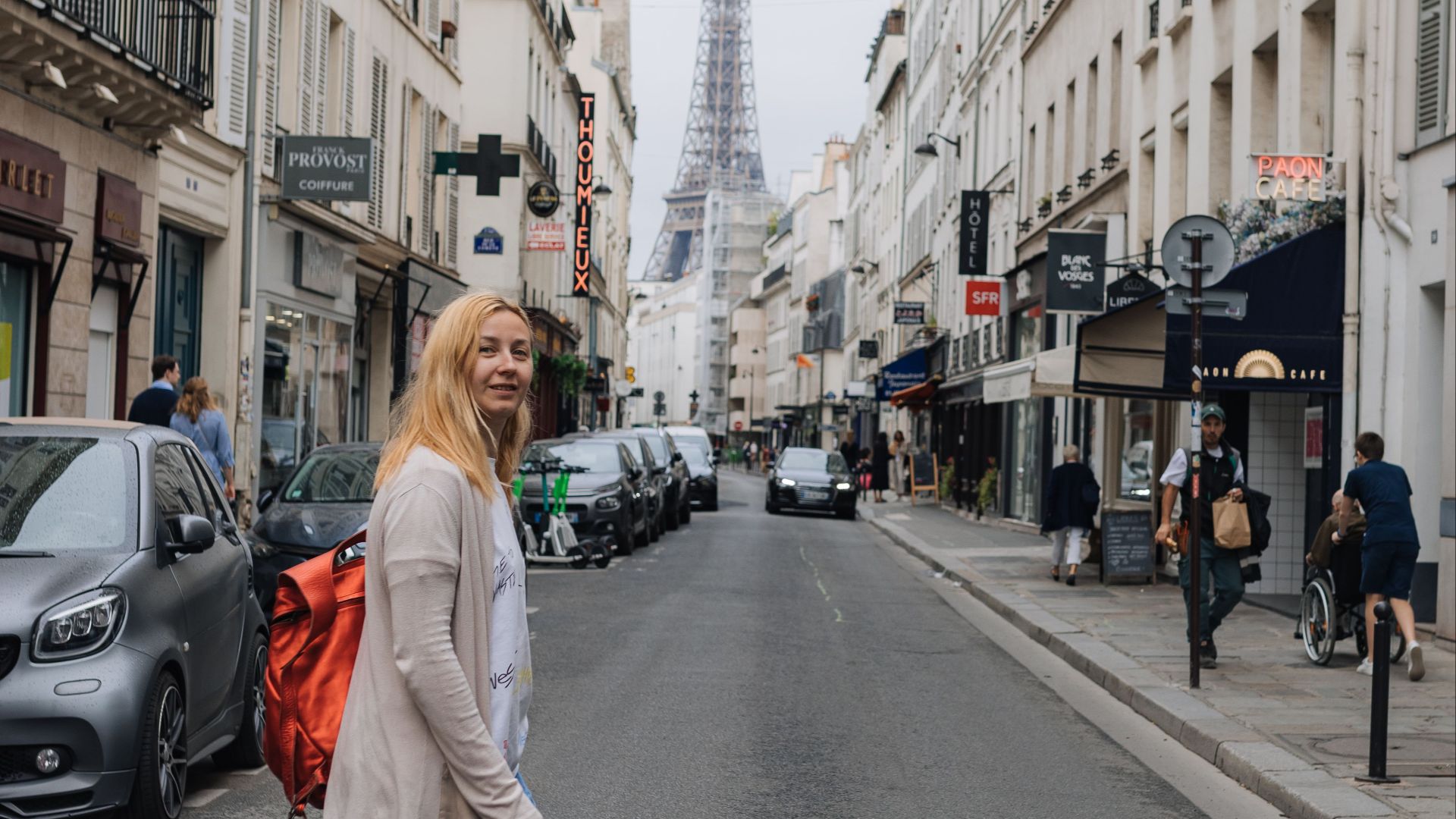 Scene of a woman strolling down a charming Paris street with the iconic Eiffel Tower in the background.