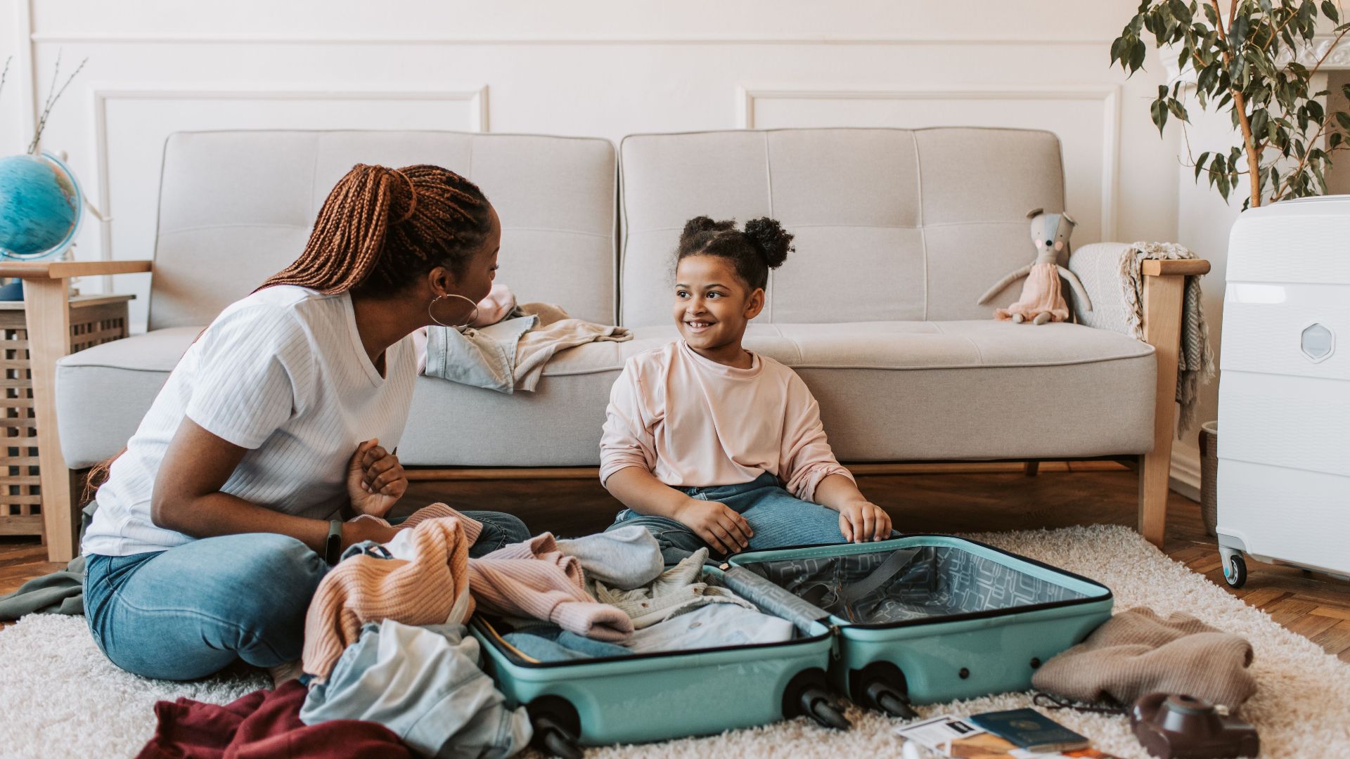 Mother and daughter packing a suitcase together at home, enjoying family time.