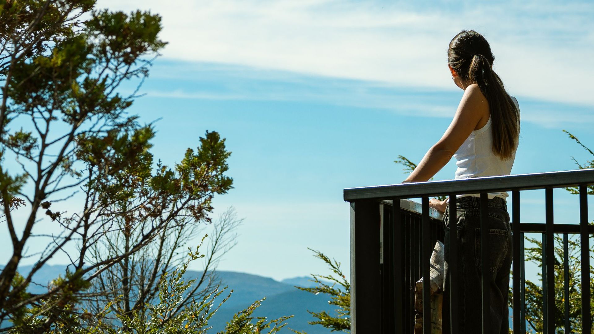 A woman standing on a balcony enjoying the scenic view of San Carlos de Bariloche, Argentina.