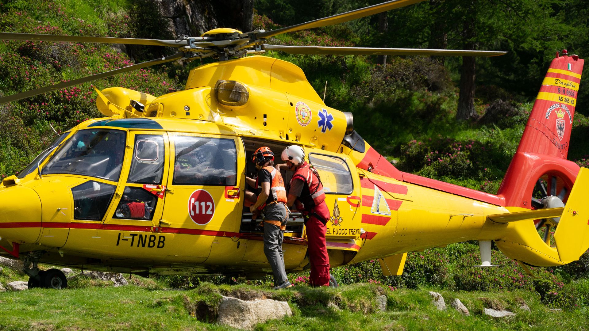 Emergency rescue team preparing helicopter in mountainous rural area.