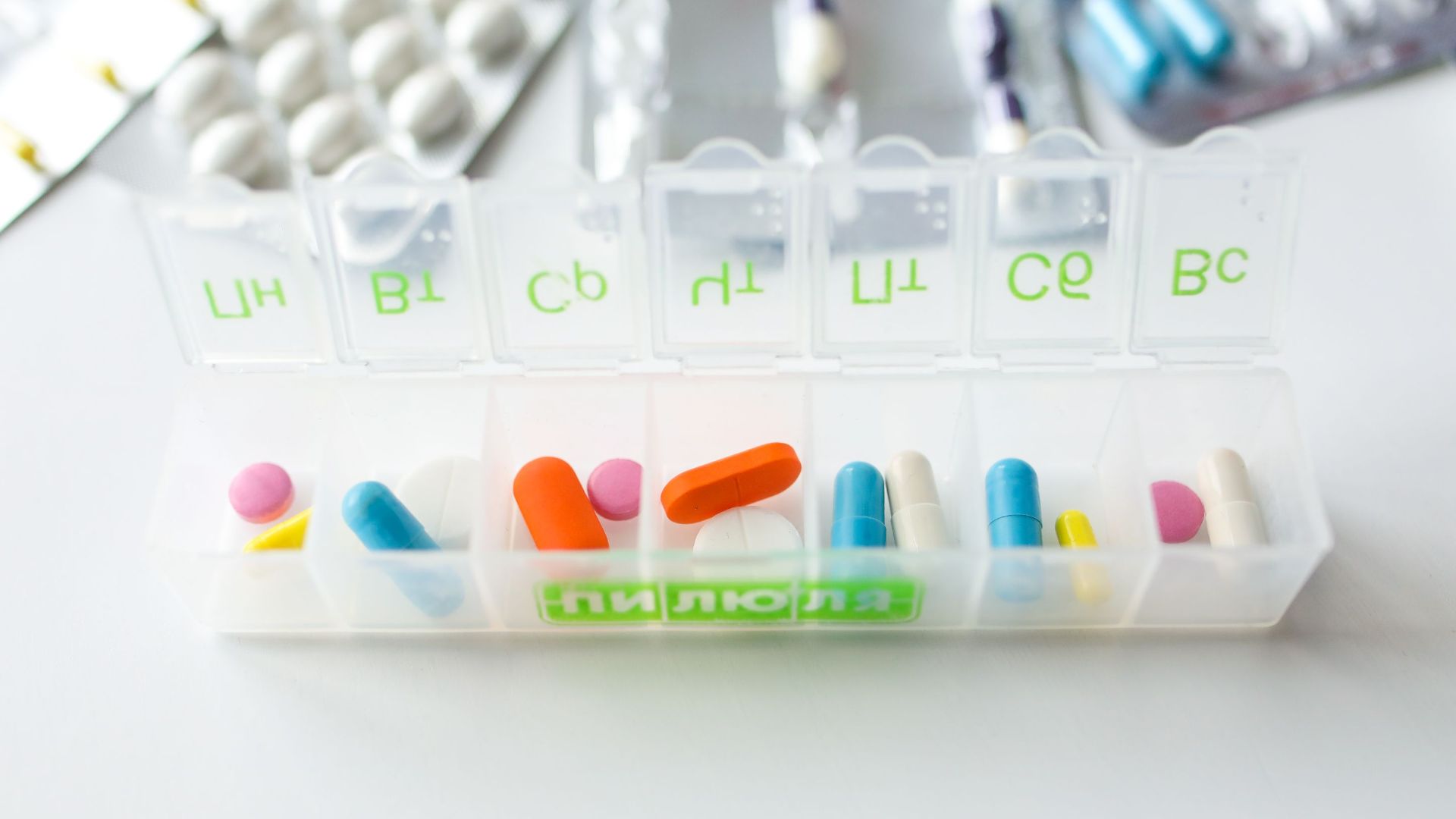 Colorful pills and capsules in a labeled weekly organizer for easy medication management.