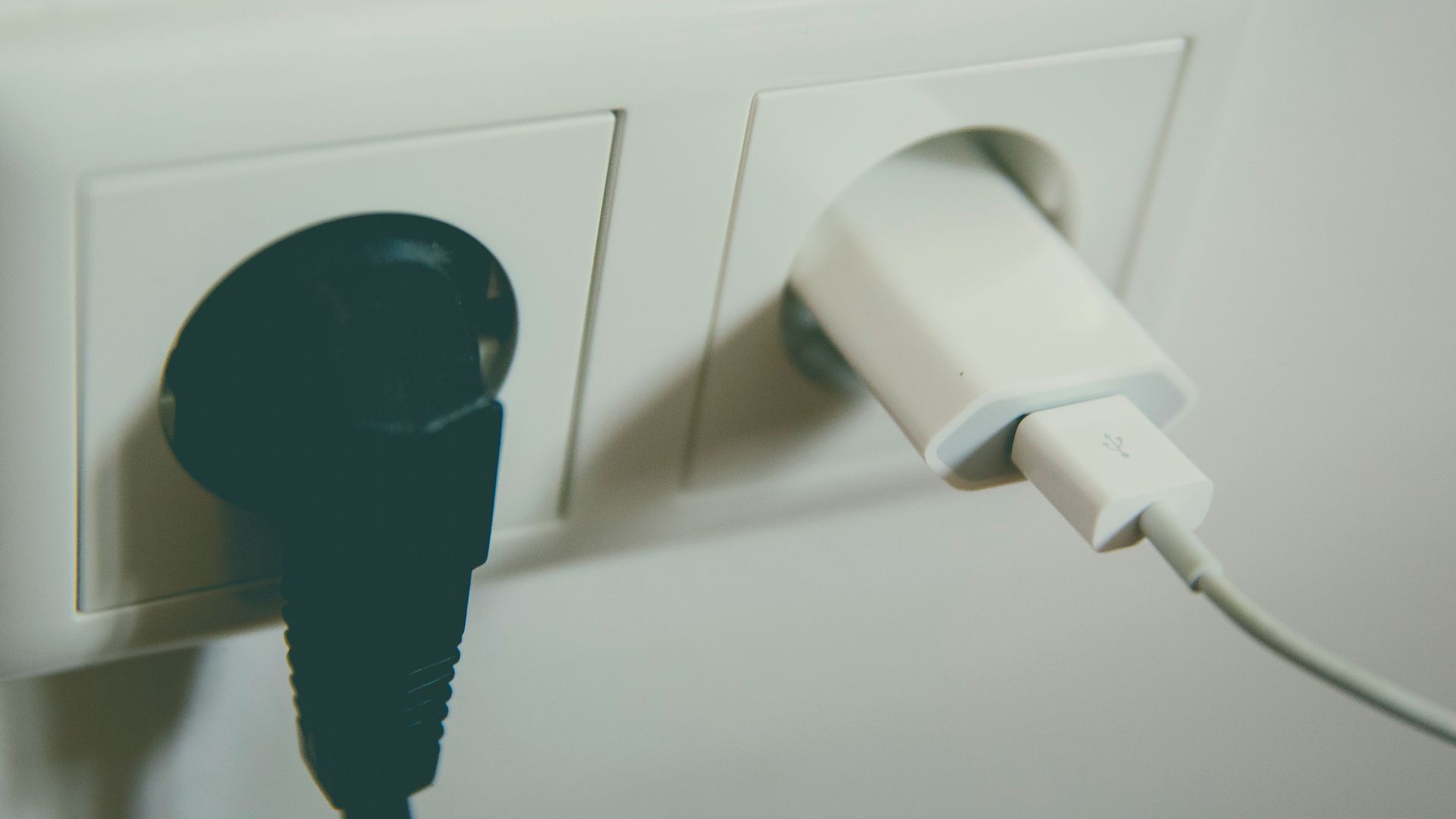 A close-up view of a wall outlet with two plugs inserted, capturing the simplicity of electrical connectivity.