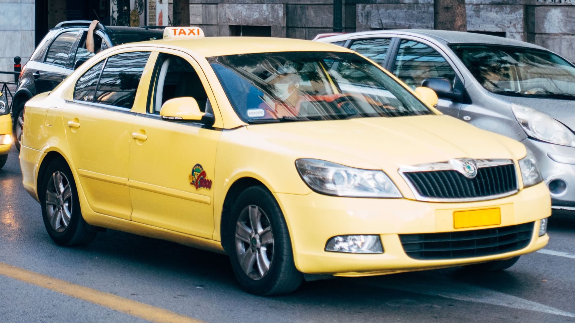 Yellow taxis lining the street in Athens, Greece, showcasing city's bustling transportation.