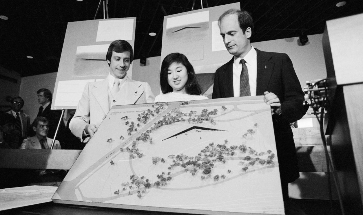 Jan C. Scruggs (left), President of the Vietnam Veterans Memorial Fund, and Project Director Bob Doubek (right) display the final design for the memorial, which will be built near the Lincoln Memorial in Washington DC. With them is Maya Ying Lin, the Yale architecture student who submitted the winning design.