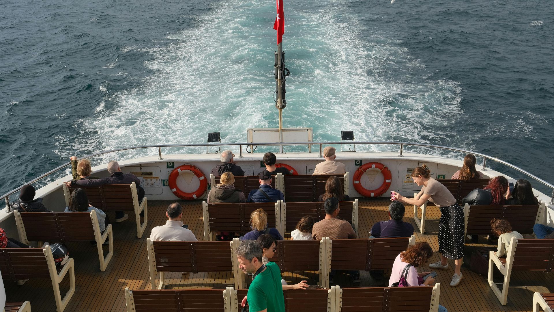 A diverse group of people enjoy a sunlit boat ride, showcasing movement and leisure.