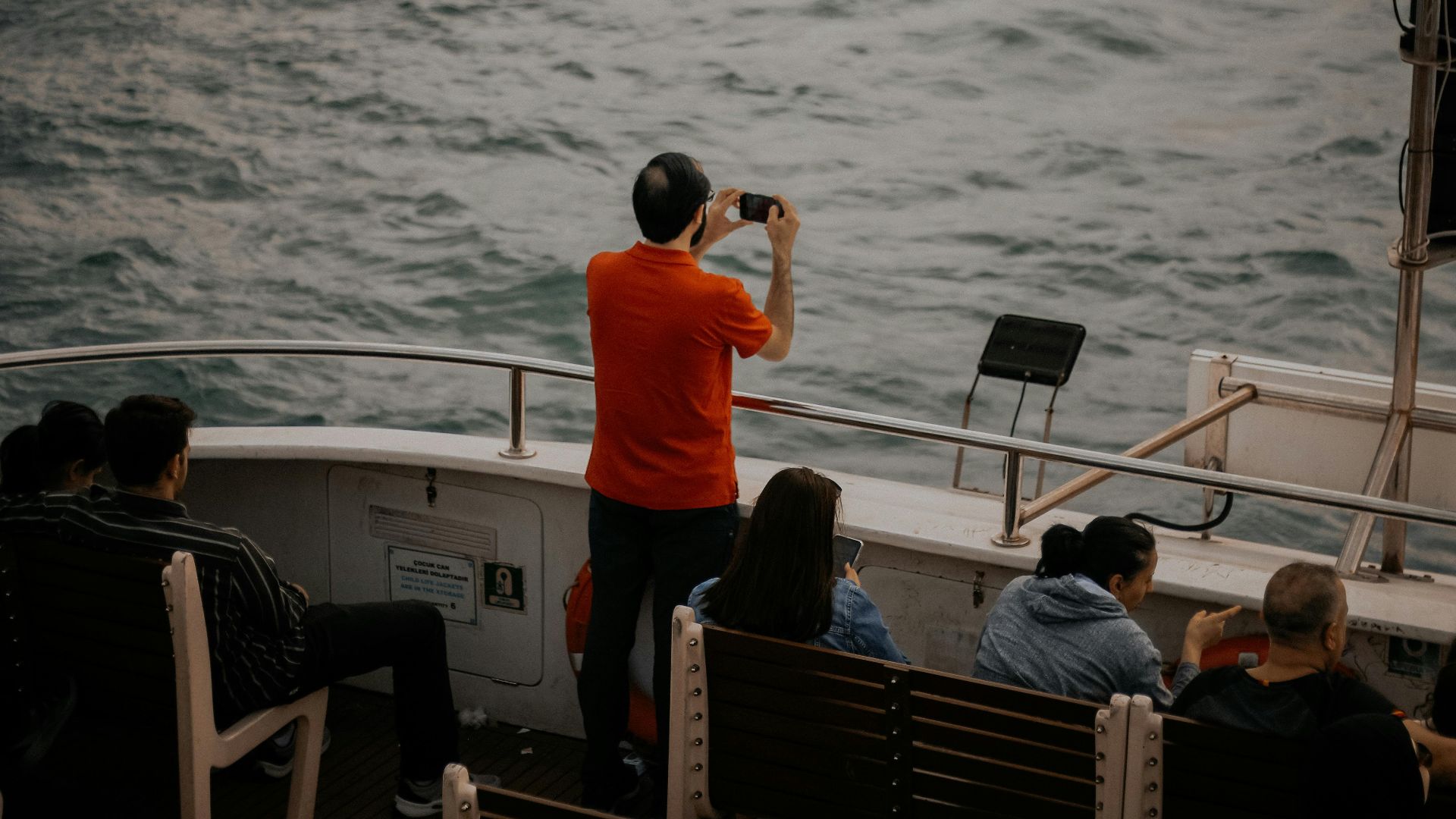 Man taking a video of the sea on a boat trip, capturing a scenic view.