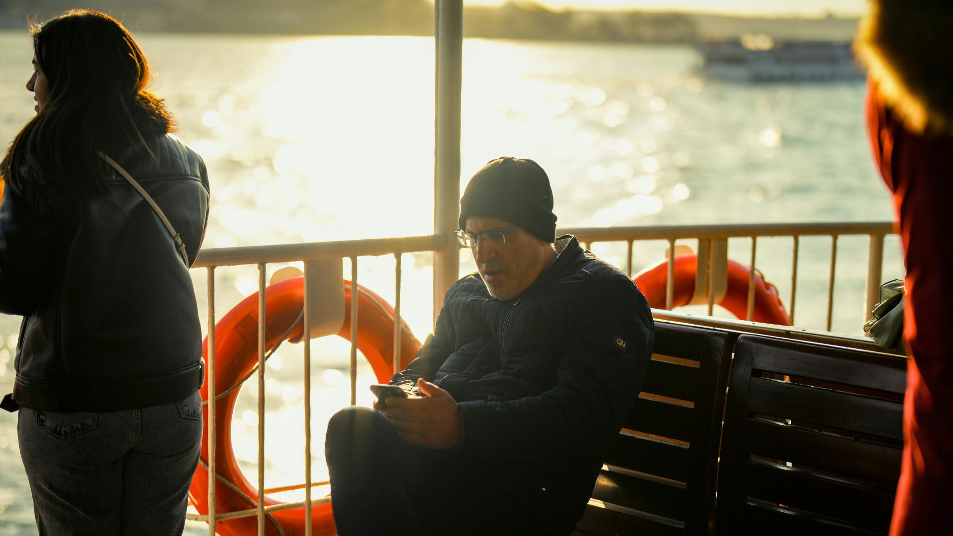 Passengers enjoying a ferry ride with warm sunlight reflecting on the water.