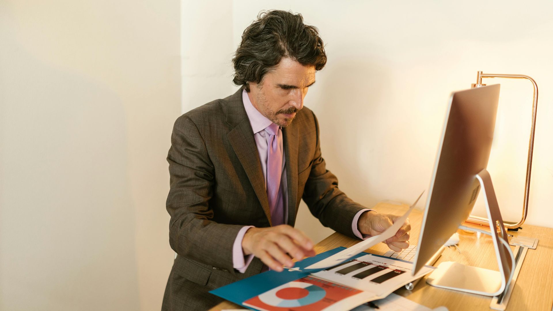 Businessman in suit reviewing financial documents in modern office space.