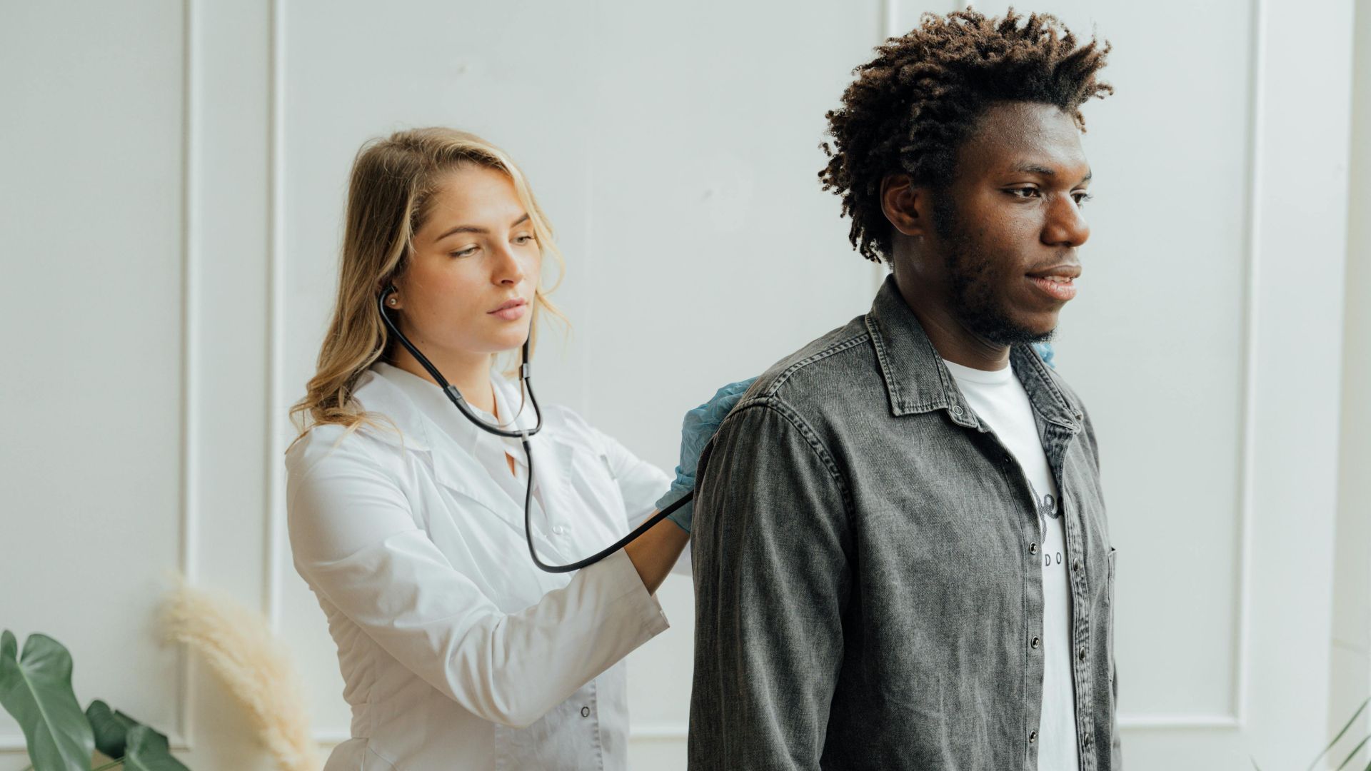 Doctor conducting check-up on patient with stethoscope indoors.