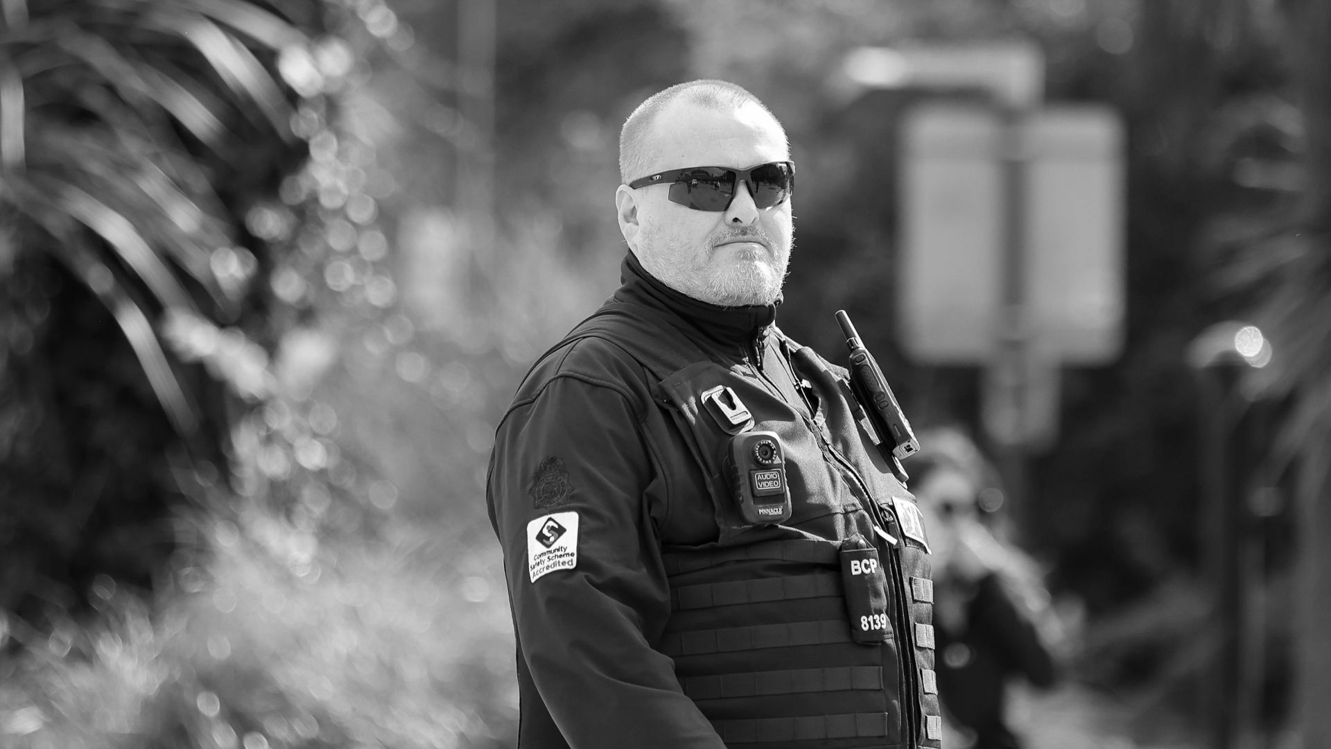 A monochrome portrait of a security guard outdoors in Bournemouth, England, showcasing professional attire.