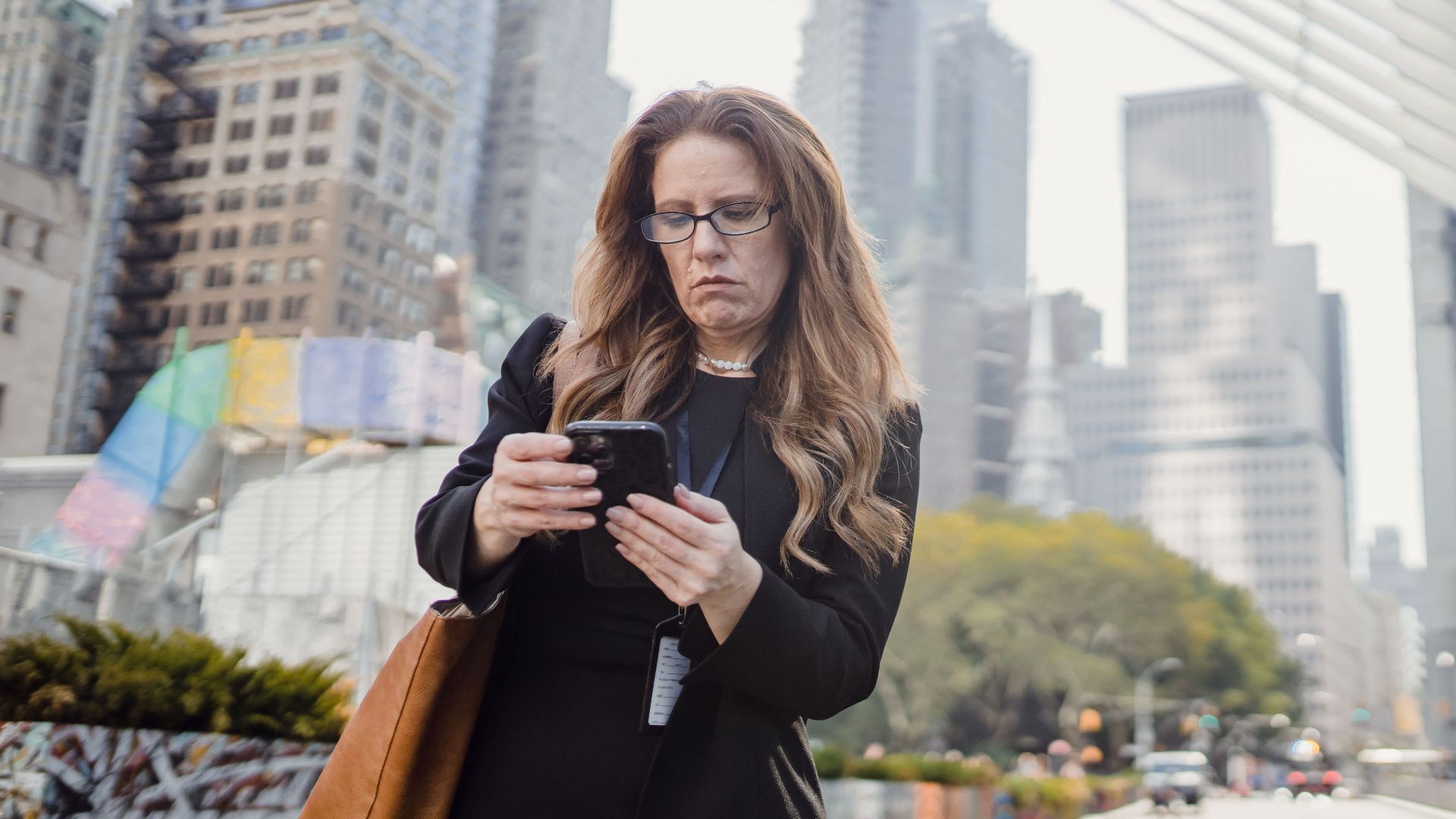 Businesswoman on phone in city street against modern skyscrapers.