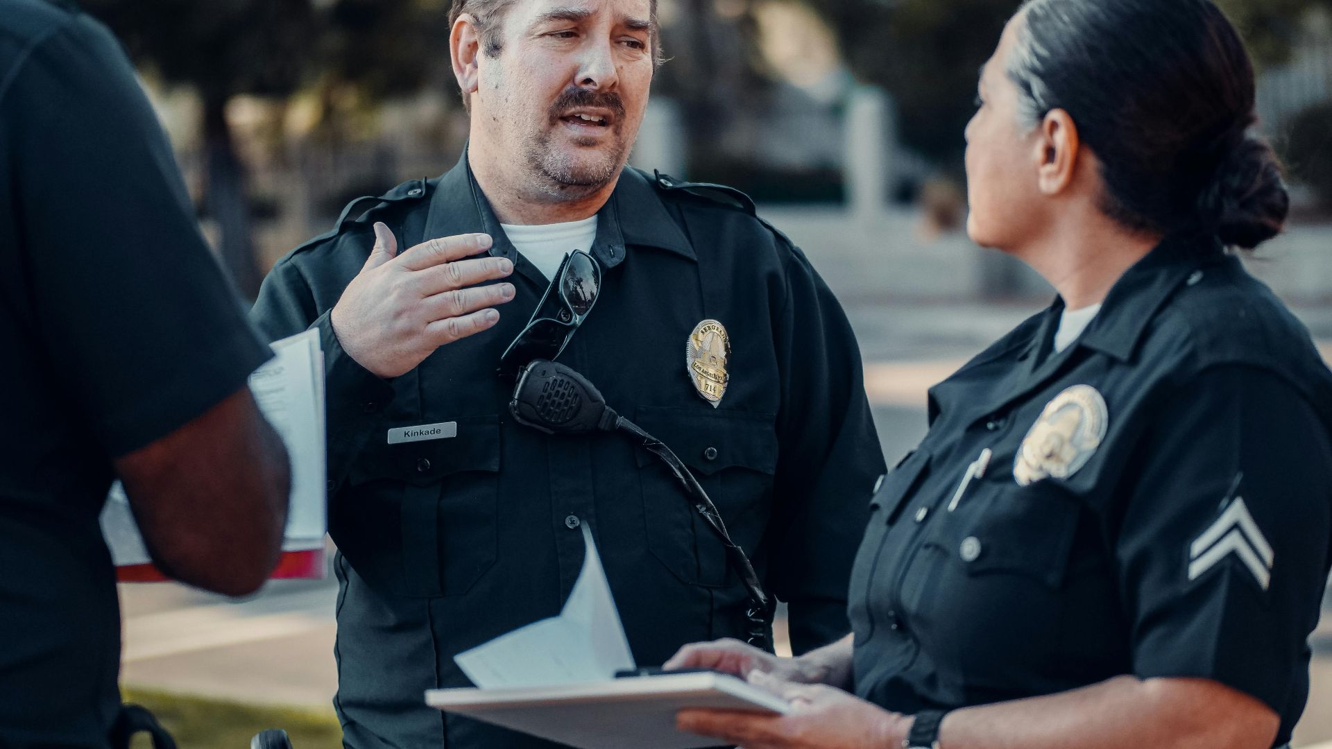 Three police officers engage in conversation outdoors, showcasing teamwork.