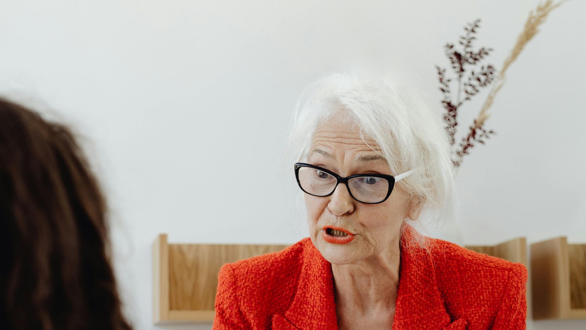 Senior businesswoman in a red blazer engaging in a professional meeting at the office.