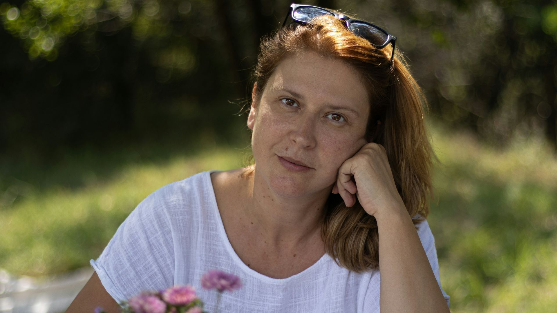 a woman sitting at a table with a vase of flowers