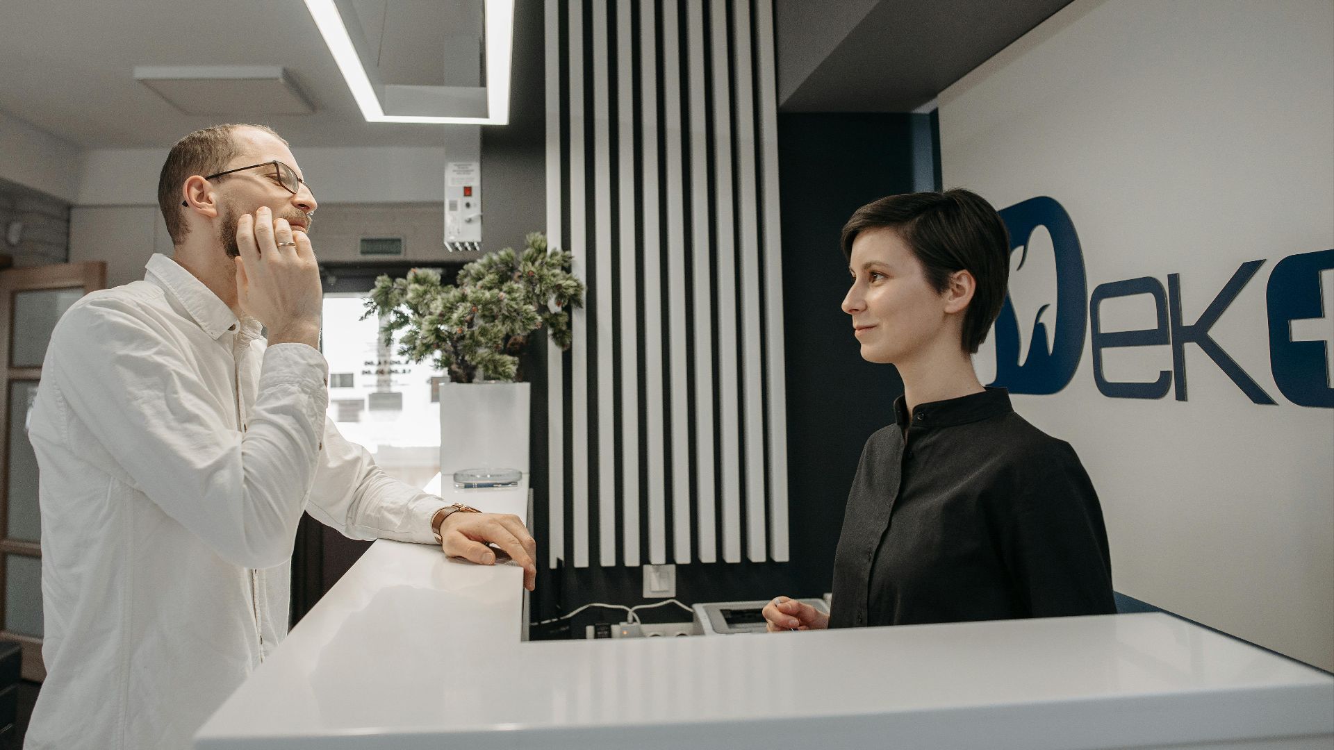 Patient discussing dental issues at a modern clinic reception with a receptionist.