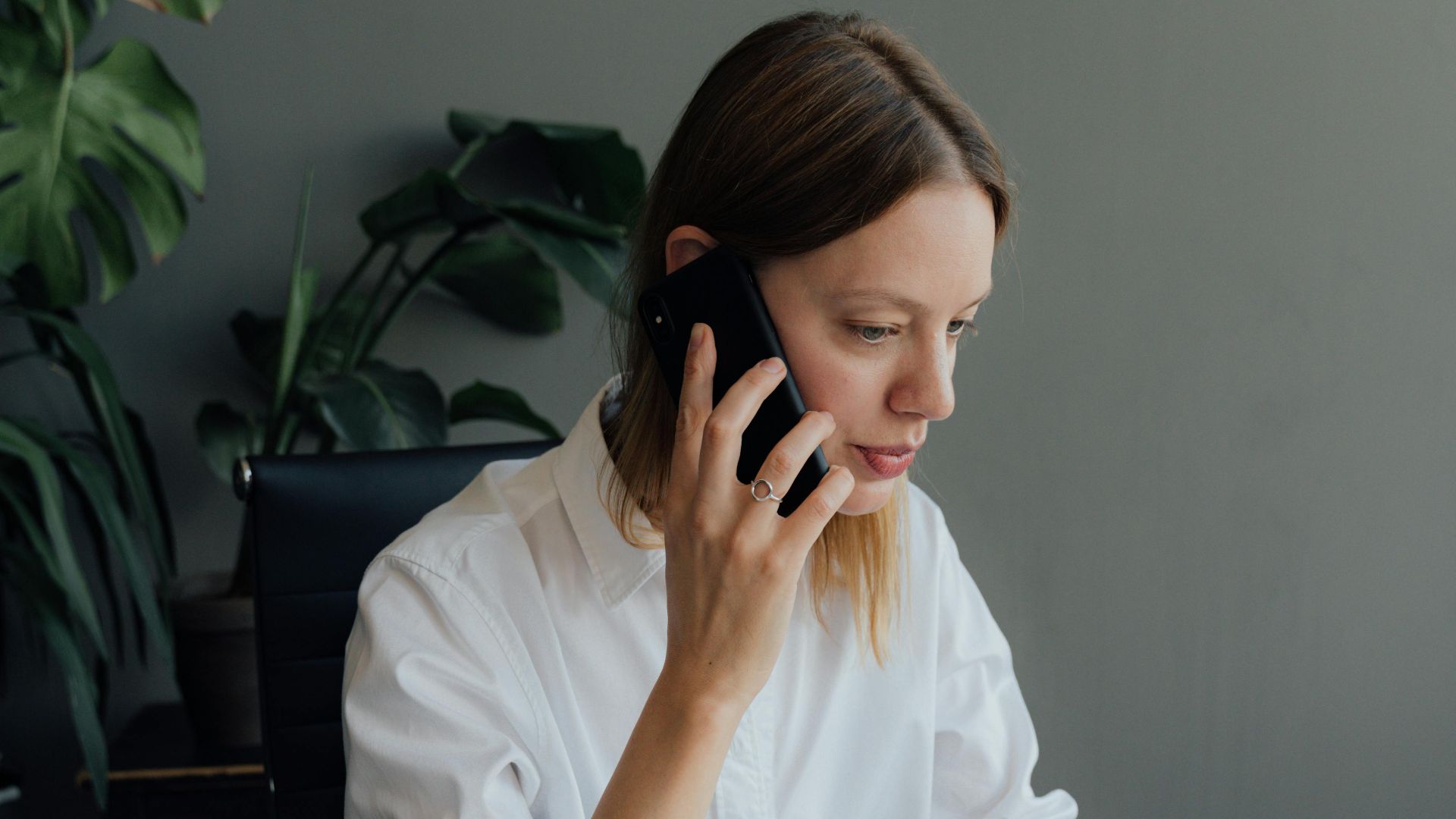 Focused woman architect discussing floor plans on the phone in an office setting.