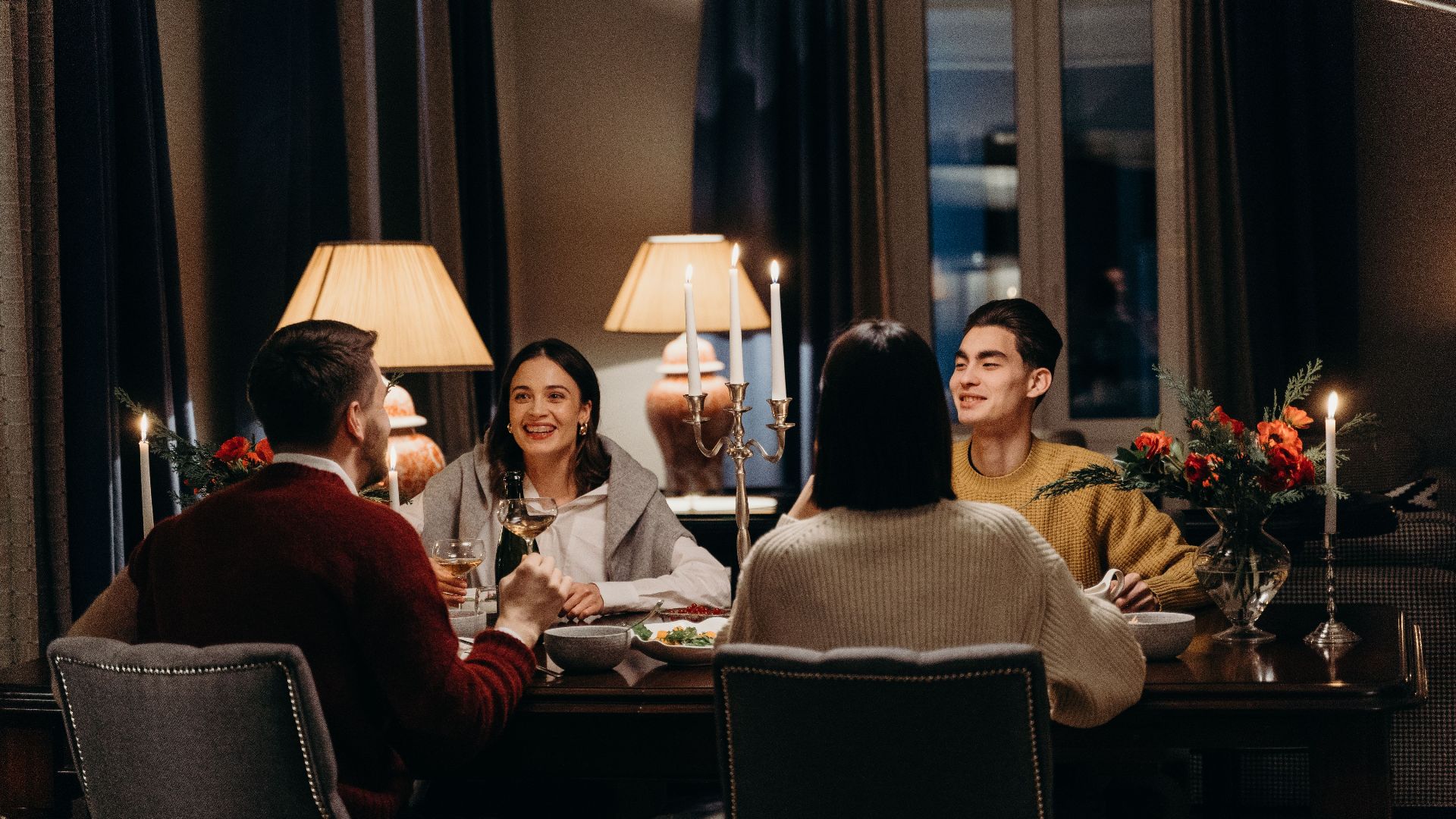 Warm indoor dinner scene with friends enjoying food and conversation.