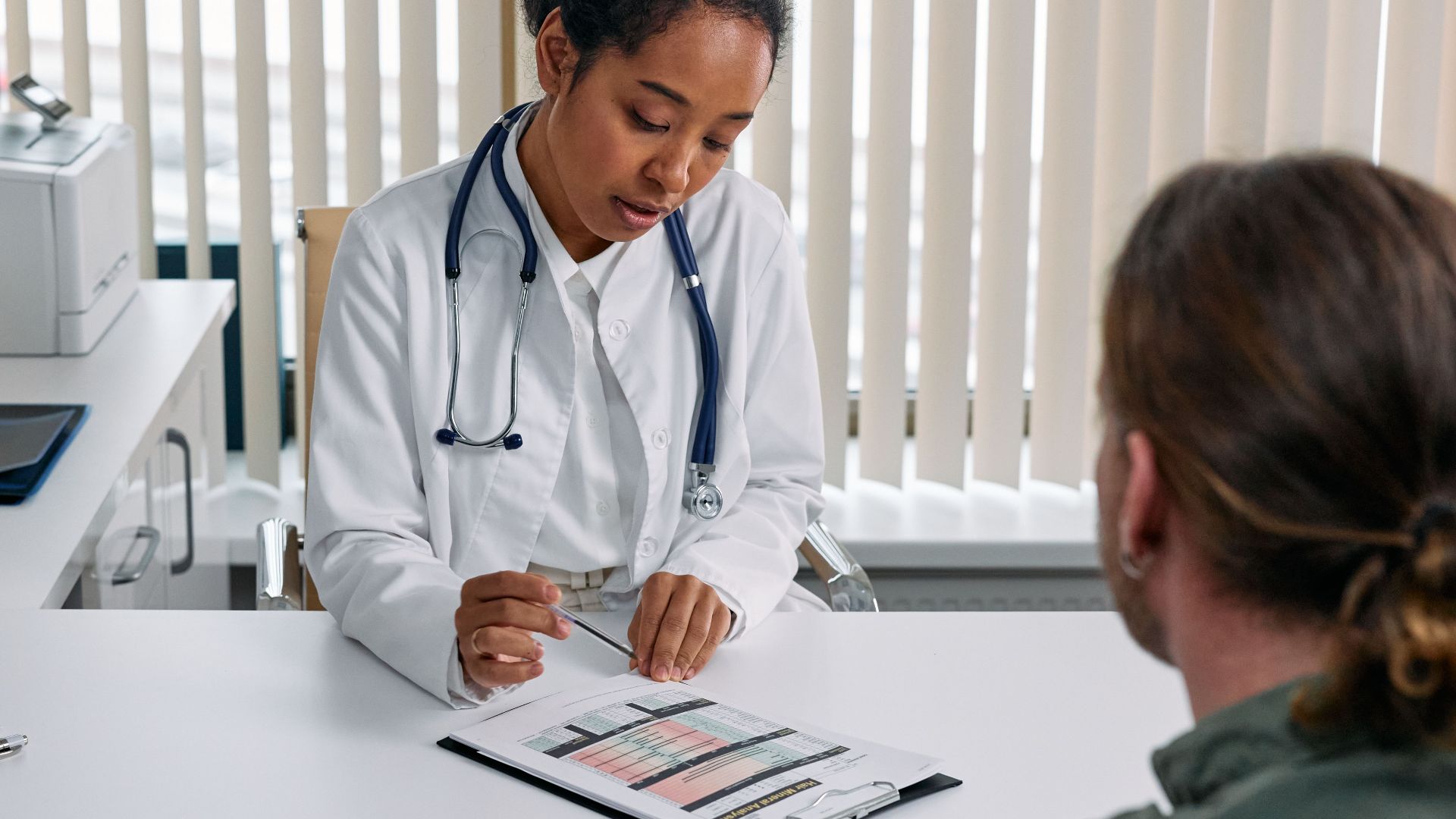 A doctor consulting with a patient in an office, discussing a medical chart.