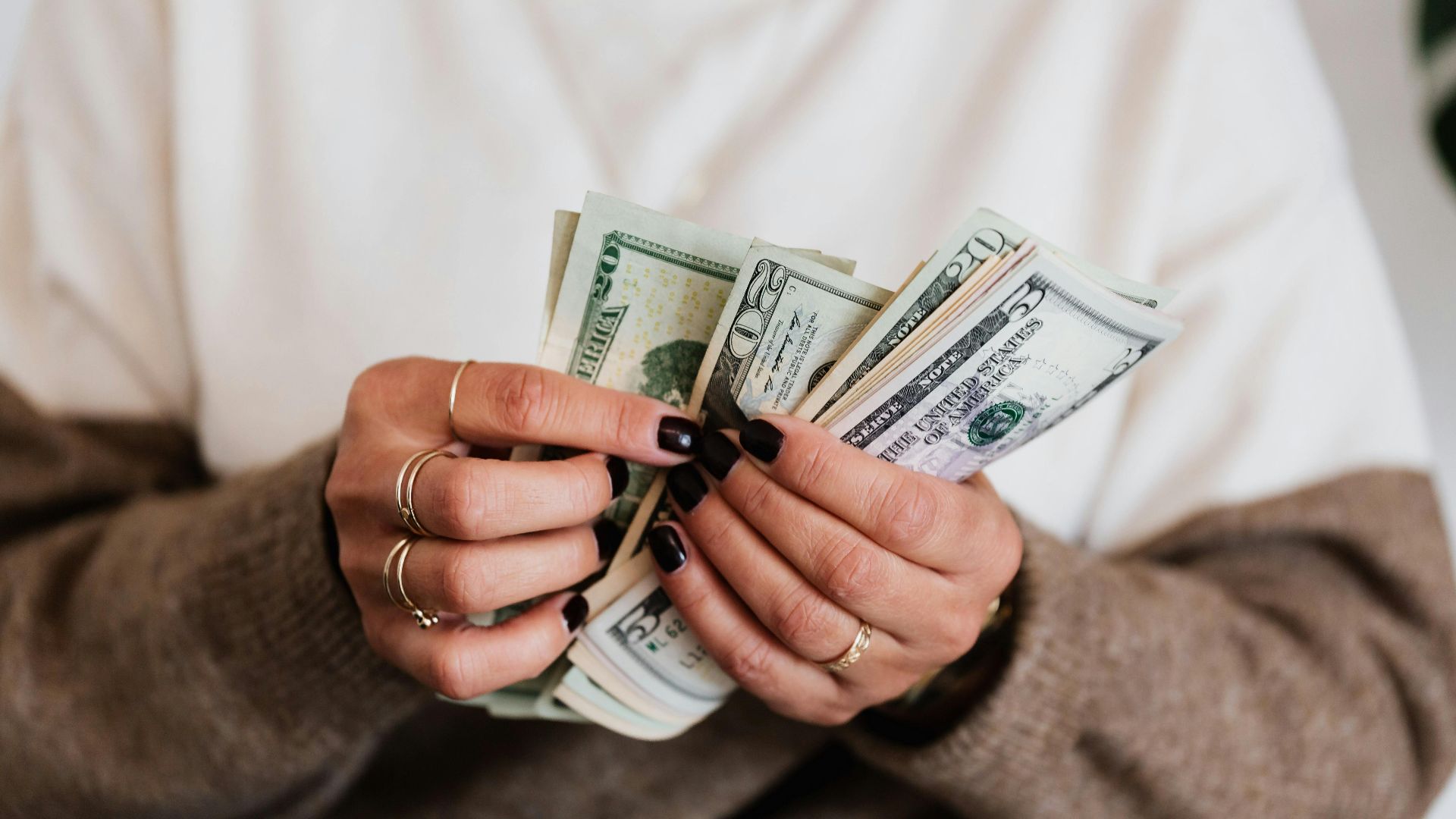 Hands holding and counting US dollar bills, highlighting finance and cash flow.