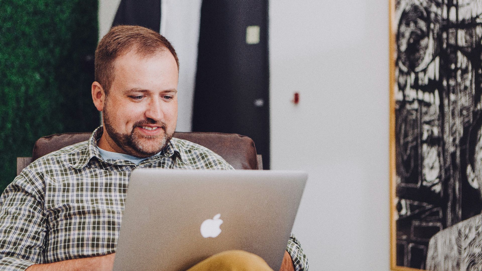 man smiling and using MacBook