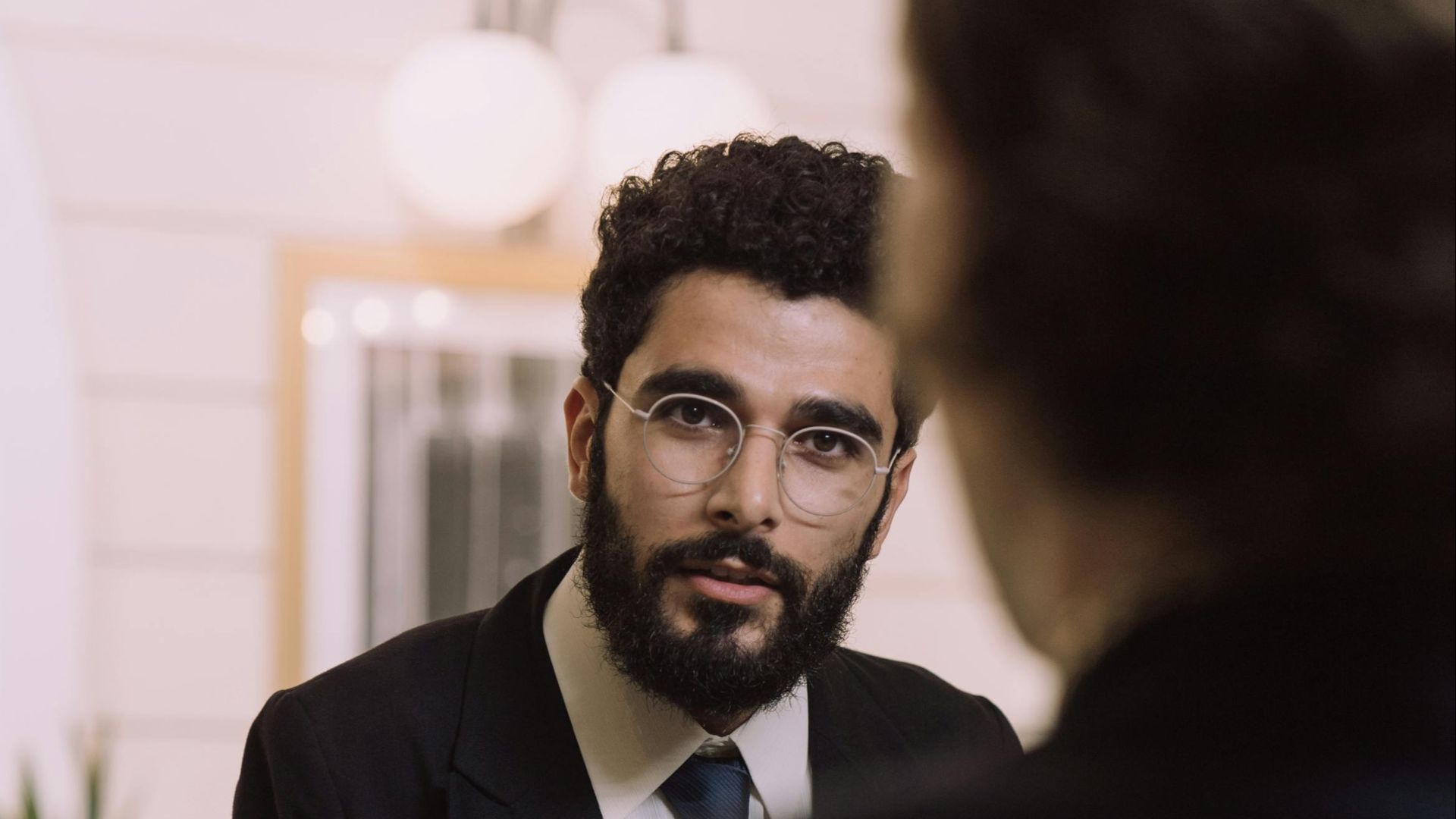 A professional businessman checks in at a hotel reception, engaging with a concierge.