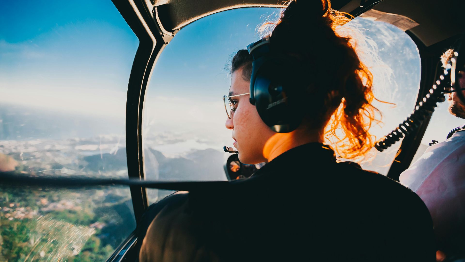 A woman wearing headphones enjoys a helicopter flight over Rio de Janeiro, capturing scenic views.