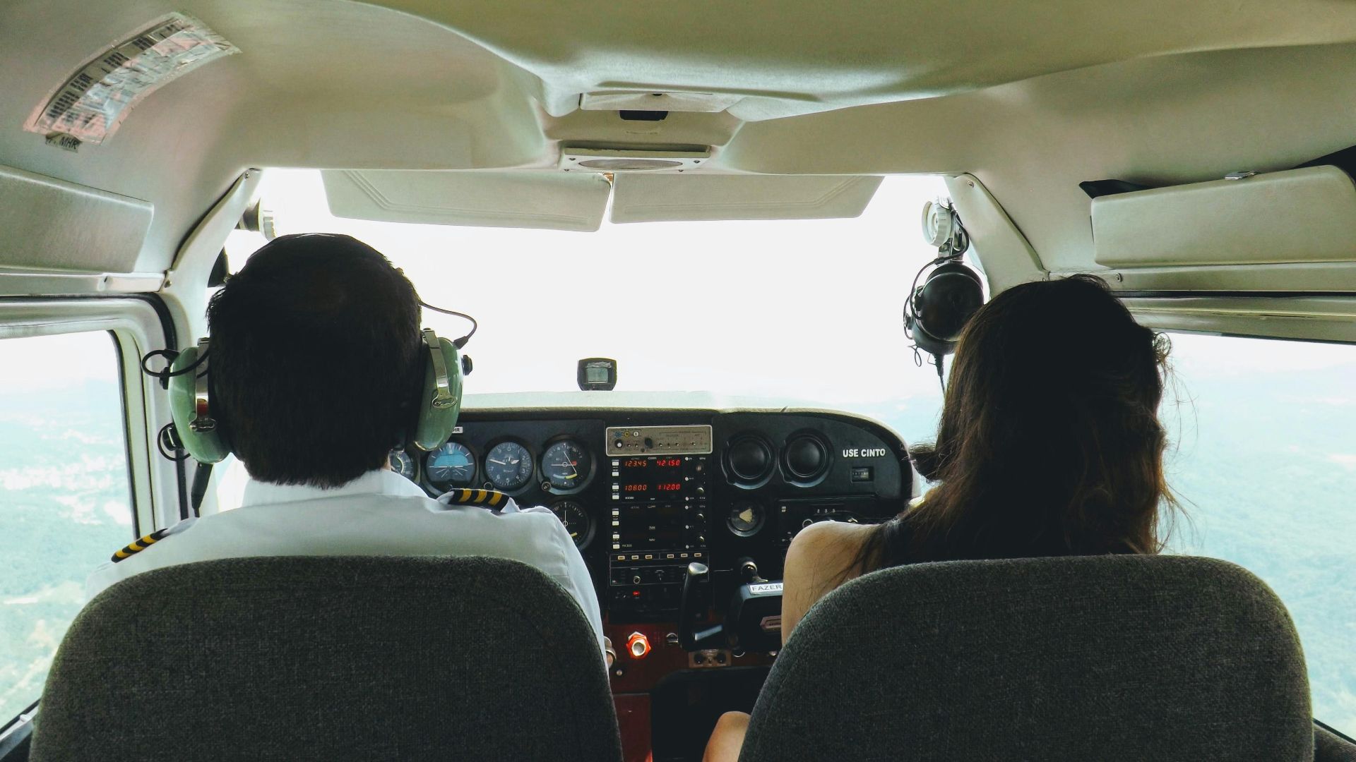 Two pilots in a cockpit navigating through the skies over Blumenau, Brazil, providing a unique aviation perspective.