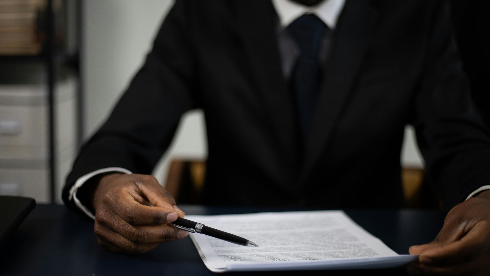 Close-up of a professional in a suit reviewing a document with focused attention.