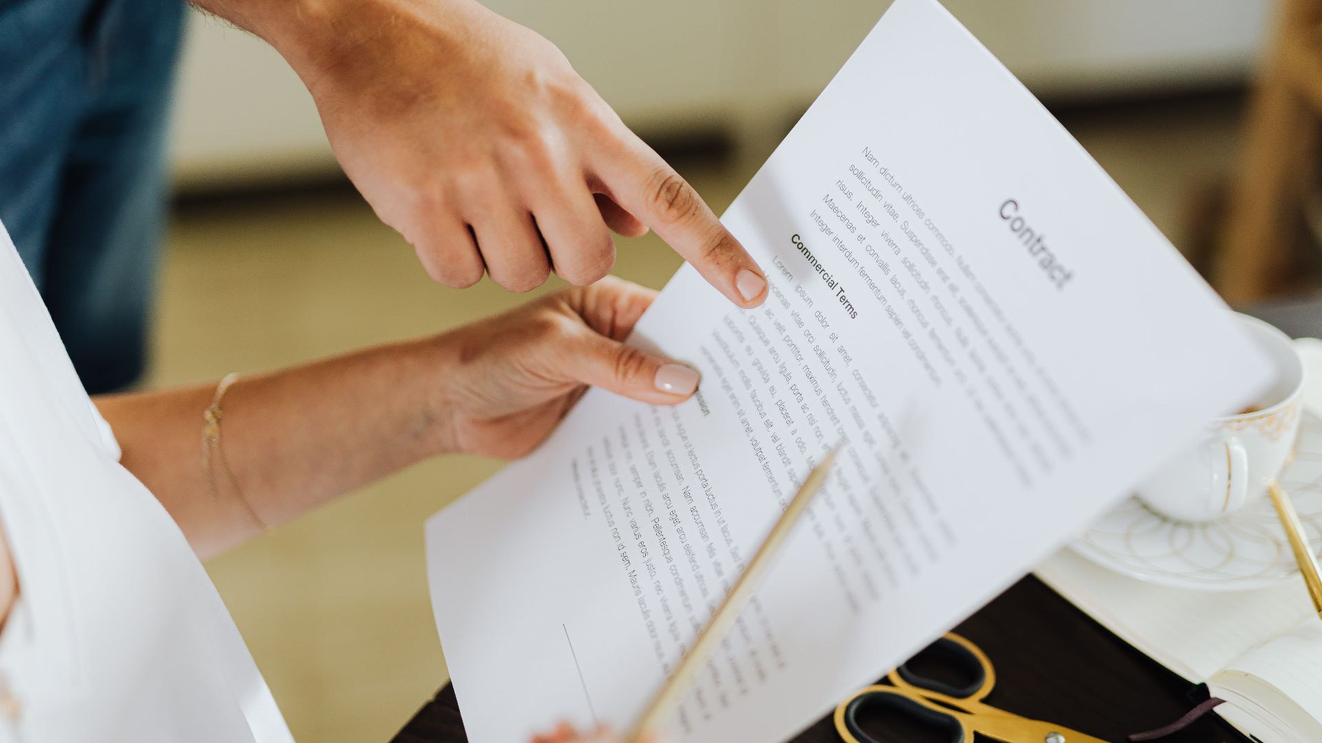 Close-up of two people discussing a business contract at a desk in an office setting.