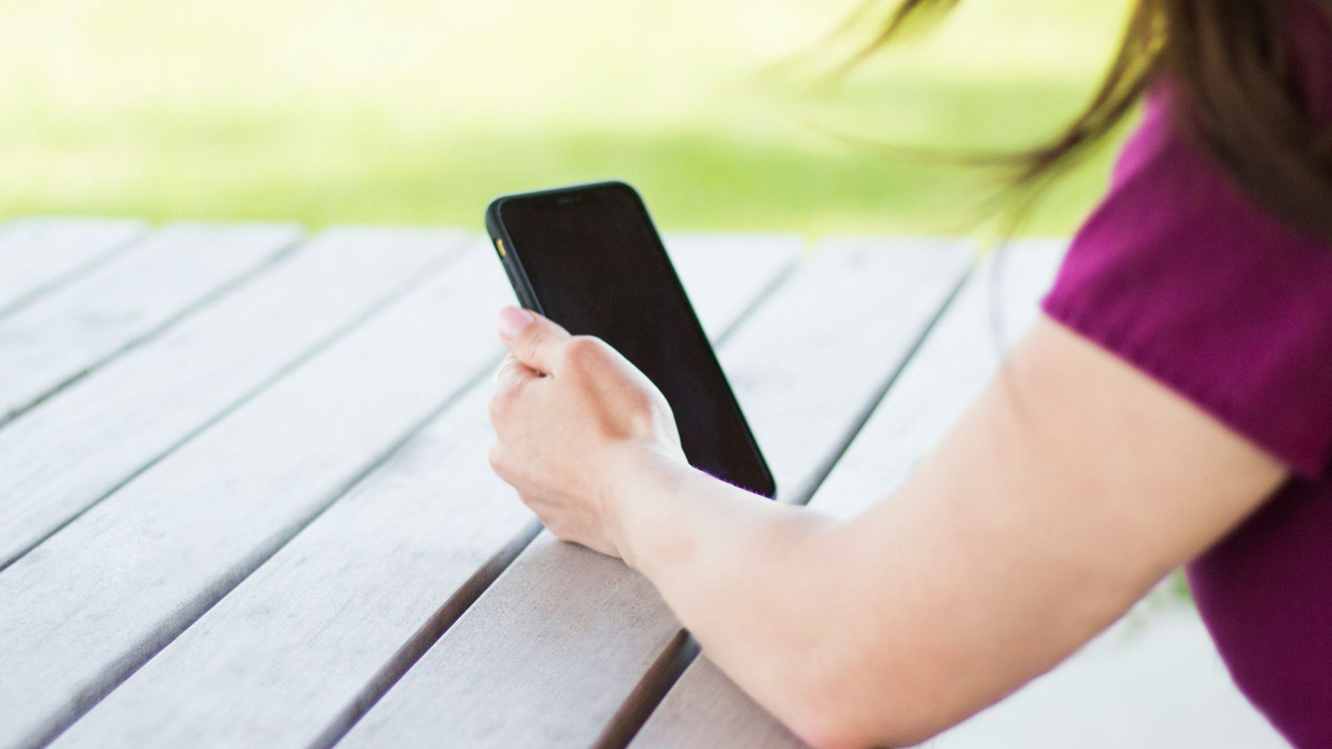 woman sitting beside table holding smartphone