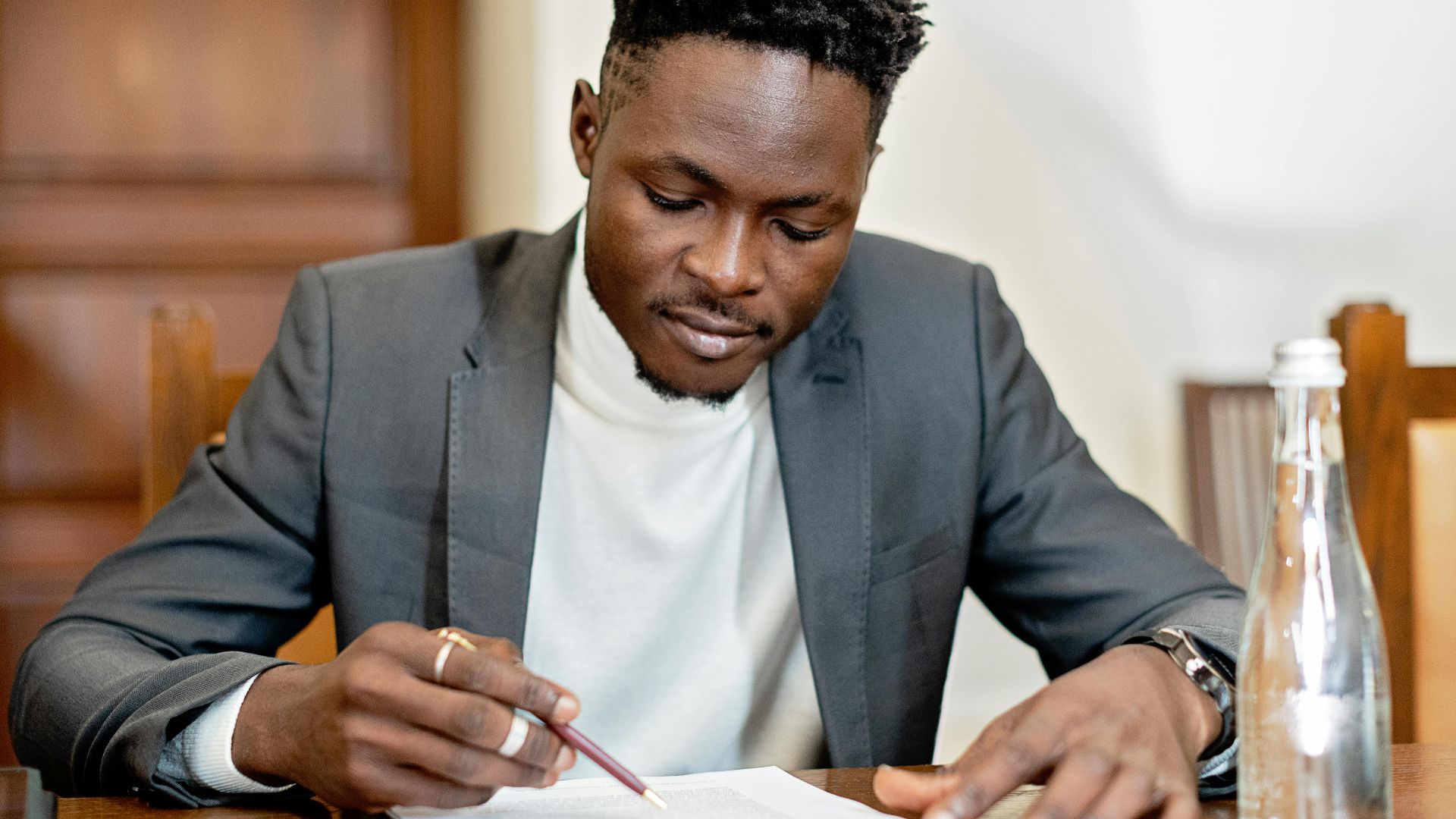 Businessman signing documents in a formal setting, focused on paperwork.