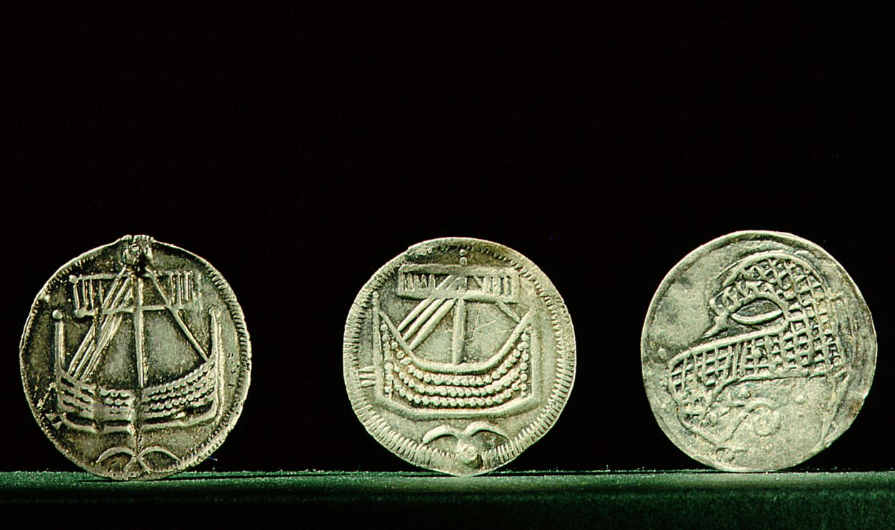 Getty Images - 152207684 - Probably minted at Hedeby, Denmark these coins were found in the Viking market place at Birka Sweden, The left and central coin show different types of ships probably merchant vessels. Denmark, found Sweden. Viking. early 9th c .